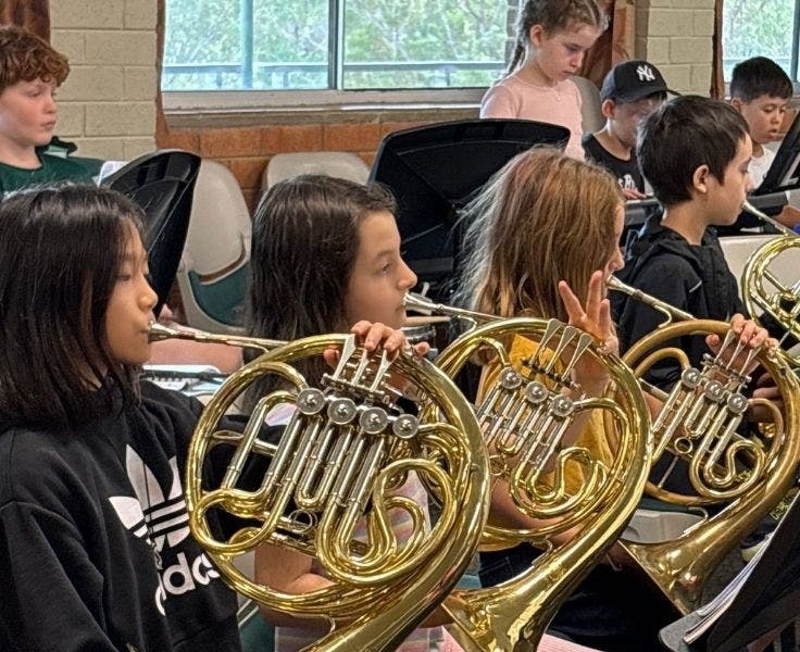Three female students playing the French horn.