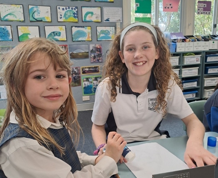 Two female students are smiling at the camera.