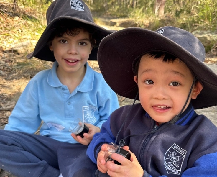 Two male students holding magnifying glasses and smiling at the camera.